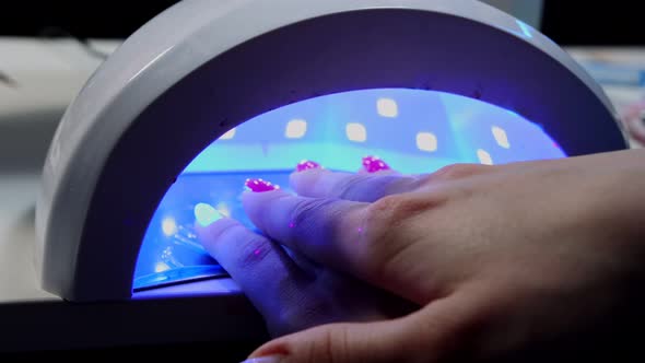 Hand of Young Woman in UV Lamp Gel Polish Manicure
