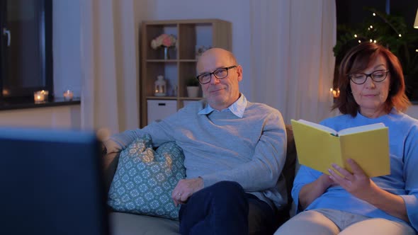 Senior Couple Watching Tv and Reading Book at Home