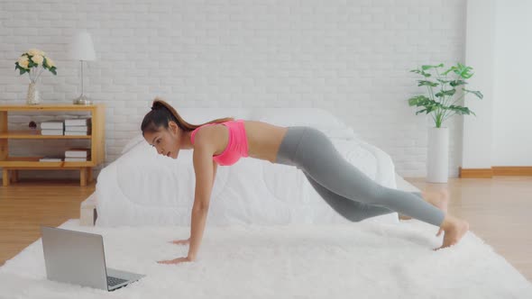 Athletic Healthy Asian woman in sportswear workout excercise online course at home