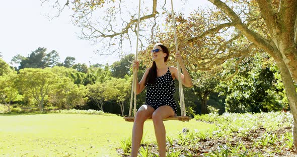 Young woman swinging on swing in park