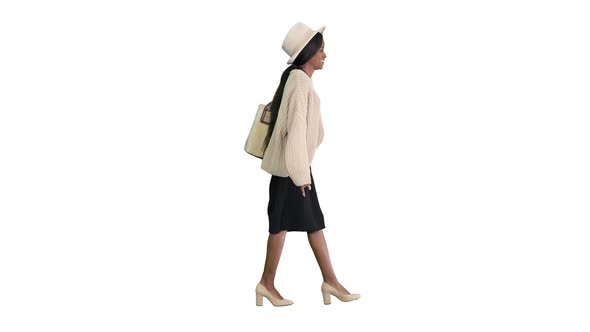 Smiling African American Woman in Knitwear and White Hat Posing While Walking on White Background