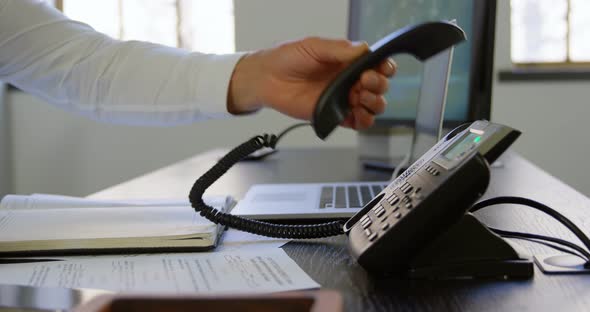 Executive putting down phone receiver at desk in office