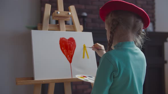 Back View of Little Artist Painting Picture on Easel