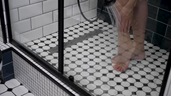 Woman Stands in Shower with Black and White Tiles