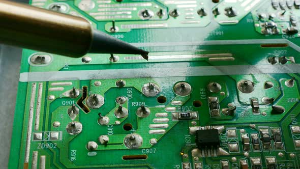 Close up shot electric solder in soldering on electronic print circuit board with hot lead