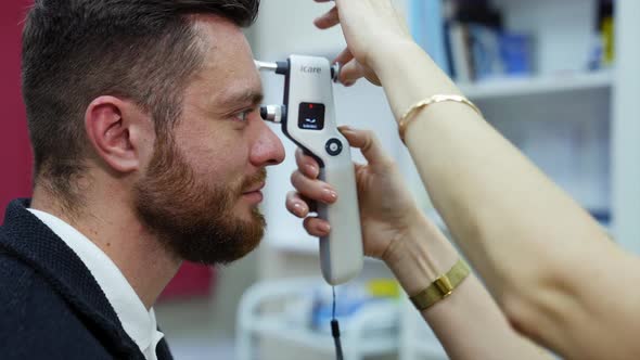 Young man checking up vision. Female ophthalmologist doing eye exam of young man