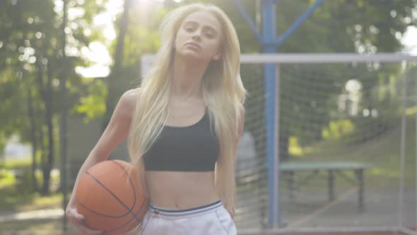 Young Slim Woman Walking in Sunlight on Basketball Court. Portrait of Beautiful Confident Blond