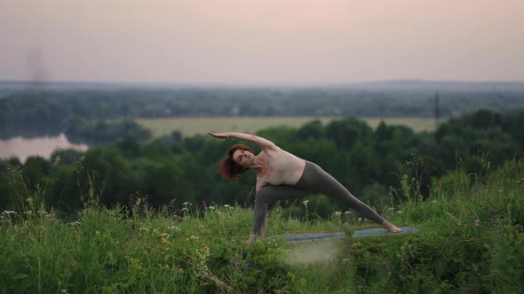 In Slow Motion a Young Woman Performs Yoga Exercises By Performing Balancing and Stretching on Top