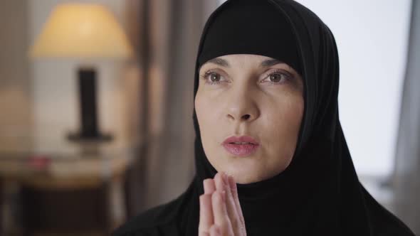 Close-up Face of Young Beautiful Muslim Woman Holding Hands Together and Praying. Lady in Black