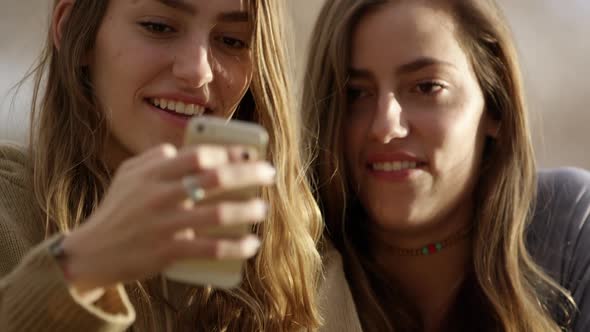 Twin teenager girls looking at smartphone and laughing