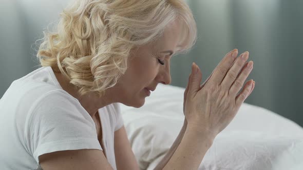 Woman of Senior Age Praying at Her Bed, Eyes Closed, Smiling, Gratitude to God