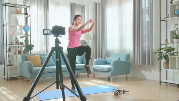 Asian Woman Blogger Shoots Video On Camera As She Does Exercises At Home In The Living Room