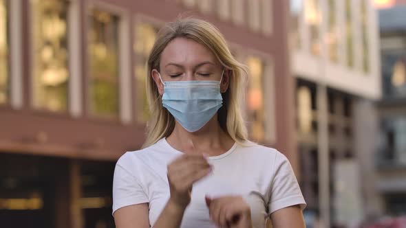 Portrait of Pretty Young Woman Looking Into the Camera and Putting on Medical Mask on Face for