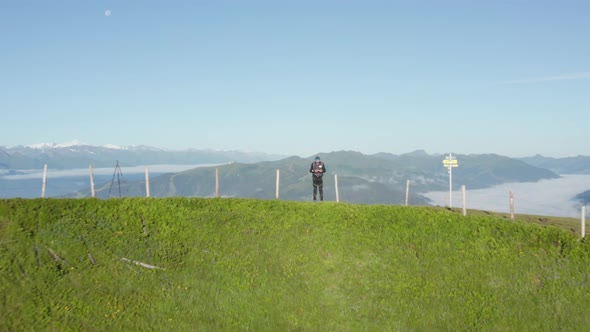 Man Controlling a Drone By the Schwalbenwand Peak with Foggy Horizon in View