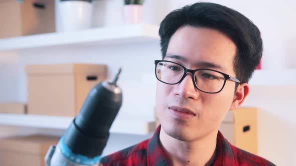 Young Asian Man with Glasses Holding Drill