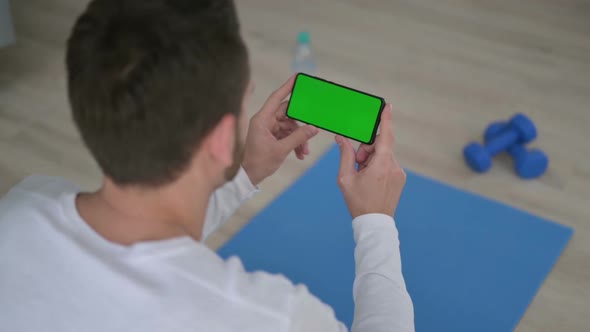 Rear View of Man Looking at Smartphone with Chroma Key Screen on Yoga Mat