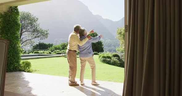 Rear view of caucasian senior couple pointing towards a directing standing near the garden