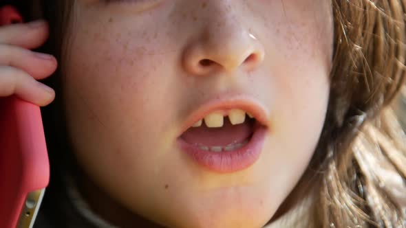 A Child with Freckles Talking on a Smartphone a Young Girl 57 Years Sitting on the Couch at Home and