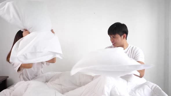 Joyful Young couple playing pillows fight on bed