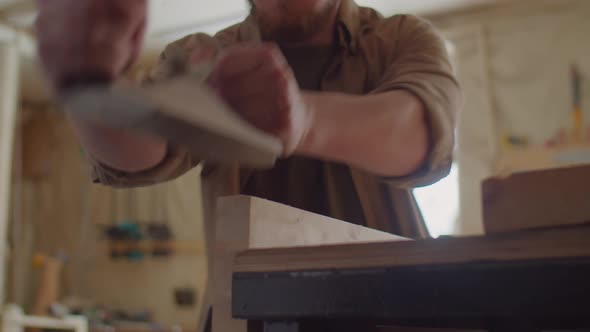 Carpenter Shaping Wooden Plank with Hand Plane