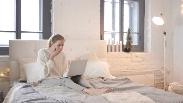 Shocked Young Girl Wondering to Results on Laptop in Bed