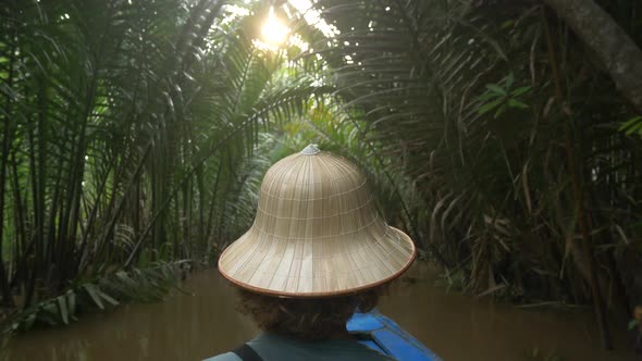 Boat tour in the Mekong River Delta region, Ben Tre, South Vietnam. Tourist with vietnamese hat on c