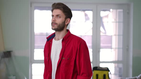 Thoughtful Caucasian Young Man Looking Around Standing Indoors Planning House Improvement