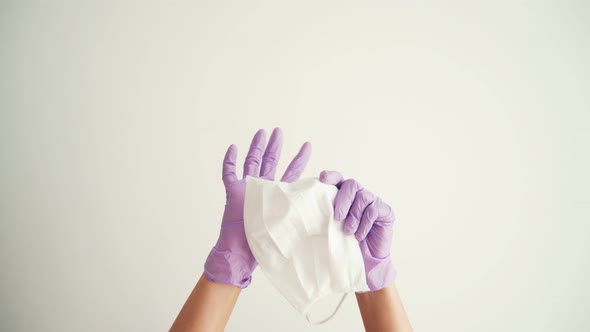 Woman Hands in Latex Protective Gloves Holding a Facial Medical Mask
