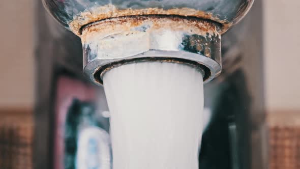 Water Flows From an Old Contaminated Tap with Calcium and Grime Into a Sink