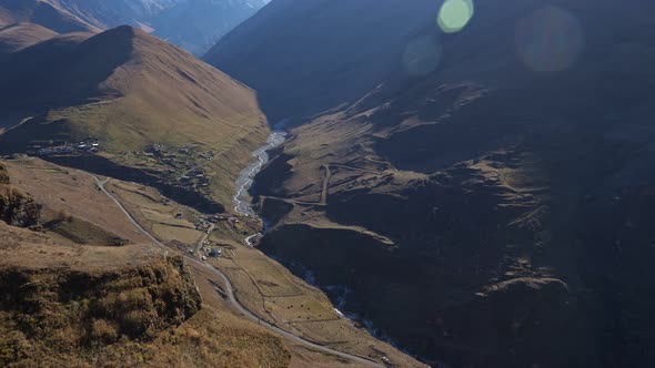 Beautiful Valley of a Mountain River with Snowcapped Peaks Towering in the Distance a Sun Glare