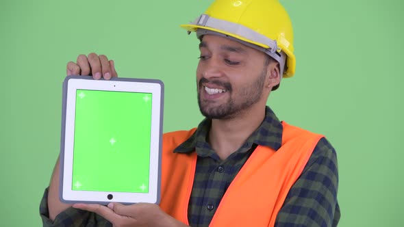 Face of Happy Young Bearded Persian Man Construction Worker Showing Digital Tablet