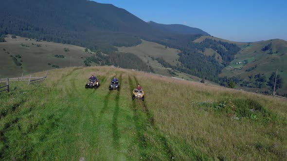 Tourists on Sport Quad Bikes on Beautiful Mountains Background
