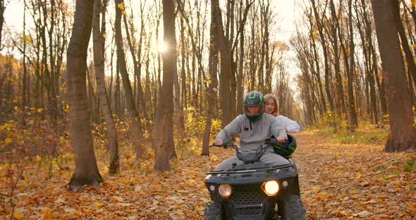 A Young Couple Rides an ATV Offroad in the Autumn Forest