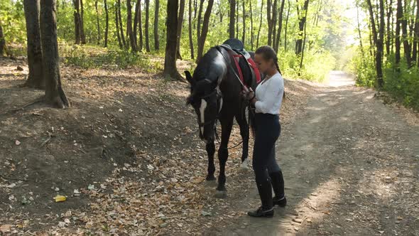 The Young Woman Gently Strokes Her Horse in the Park, While Trying To Train Him