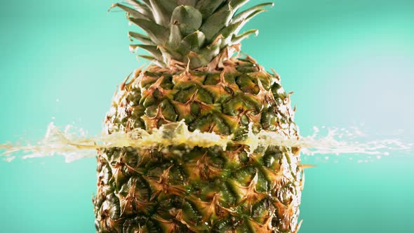 Half Pineapple Falling and Splashing on Turquoise Background