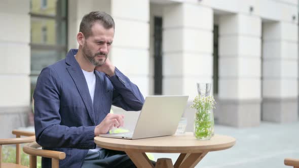 Man Having Neck Pain While Typing on Laptop