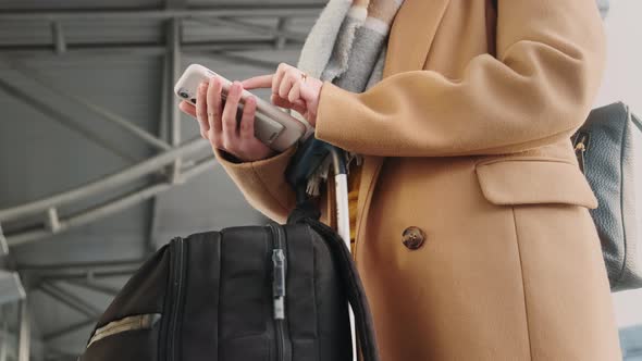 Bottom Side View of Woman Without Face Wearing Beige Coat Wool Scarf Standing Inside Airport