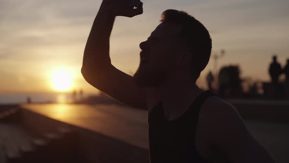 Tired Runner Is Pouring His Head By Water From Bottle After Jog in Evening