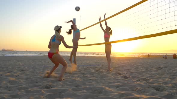 Women players play beach volleyball and a player hitting spiking the ball.