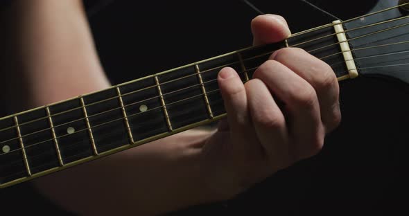 Fingers playing on the fretboard of a guitar