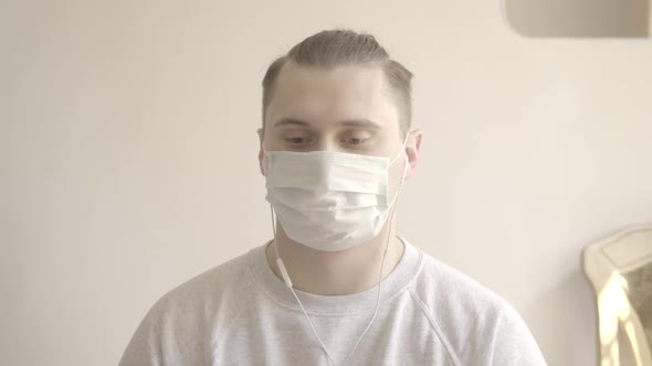 Young Man in Face Mask Agreeing with Someone in Video Chat. Portrait of Brunette Caucasian Guy with