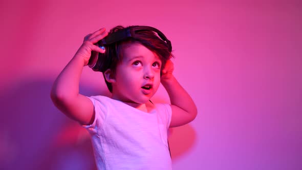 Boy in a White t Shirt Is Listening To Music on Headphones Against a Wall