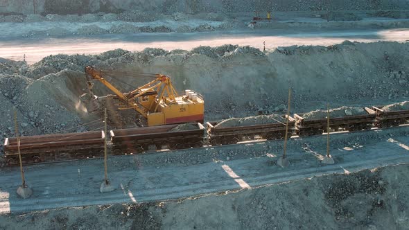 Large excavator loading rock formation it to the freight train. Gold mining.