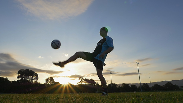 Soccer (Football) Player Juggles a Ball at Sunset