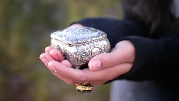 Close up on a woman holding a cute silver vintage jewelry box in her hands.
