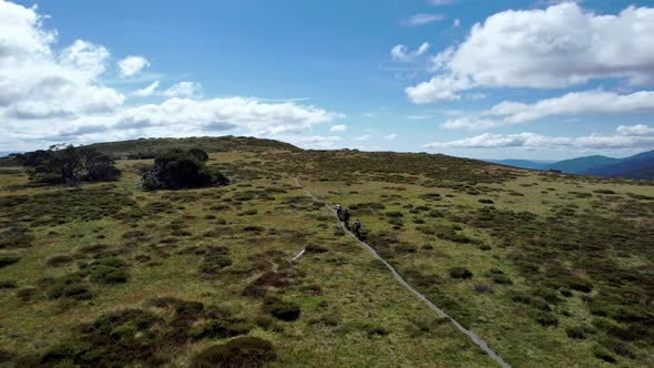 Drone following mountain bikers along a trail on top of a mountain in the sunshine. The drone closes