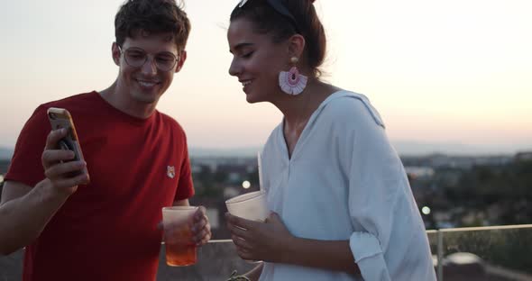 Young man showing his smartphone and talking with young woman