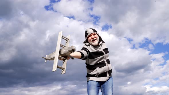 Happy Greybeard Man Imagine Flying on Wooden Plane in Sky Pretend Fly