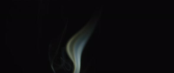 A single flames of incense burning in the dark alt