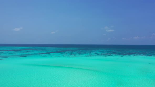 Wide angle fly over abstract shot of a sandy white paradise beach and blue water background 